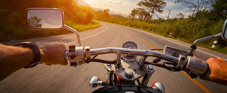 Driver riding motorcycle on the empty asphalt road