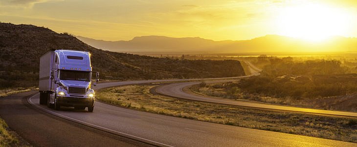 18-wheeler tractor-trailer truck on interstate highway at sunset
